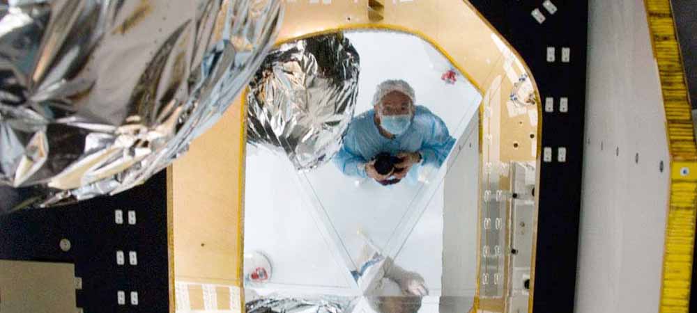 Photographe en tenue stérile photographiant une installation technique brillante, image mêlant innovation, technologie et créativité visuelle.