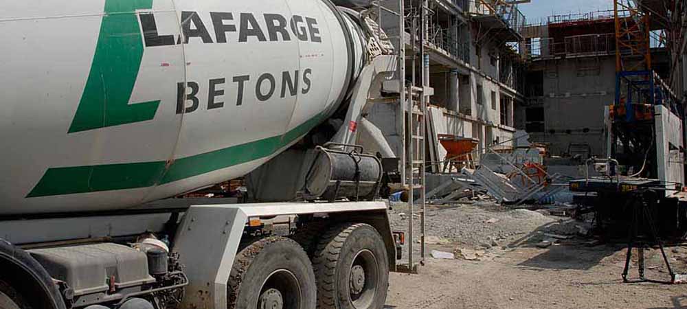 Camion toupie Lafarge Betons sur un chantier de construction, livraison de béton prêt à l'emploi, environnement de bâtiment en cours d'édification, matériel et échafaudages visibles en arrière-plan.