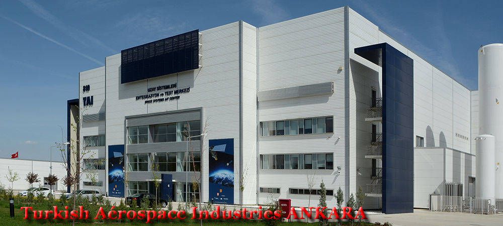 Siège moderne de Turkish Aerospace Industries (TAI) à Ankara, bâtiment industriel blanc avec vitrages et enseignes en turc et anglais, partenariat avec Thales en Turquie, spécialisé dans l'aérospatial et la défense.