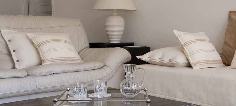 Salon élégant et épuré avec canapé blanc, coussins assortis et table basse en verre